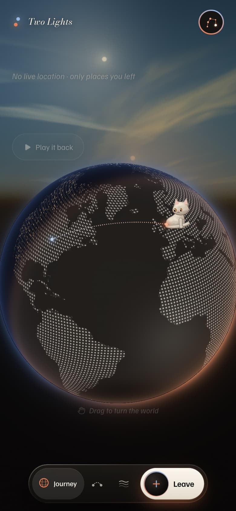 A dotted globe with two lights and a small paper cat sitting on it